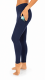 A side-profile view of a model wearing navy blue high-waisted leggings with a side pocket holding a phone, shown against a plain white background.